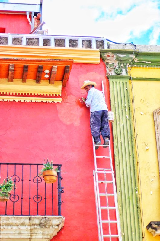 はしごに上ってペンキを塗る男性