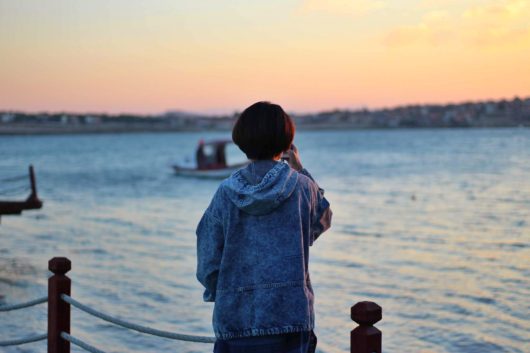 海をバックに立つ女性